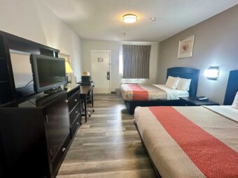 2 double beds, night stand with telephone, art image, wall light, wooden drawer unit with TV, desk and lamp, fridge with microwave, laminate flooring