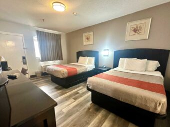 2 double beds, night stand with telephone, art images, wall light, unit with TV, desk with chair, laminate flooring