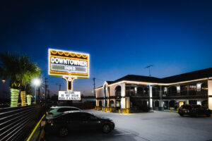 Brand signage, two story building with covered walkways and exterior guest room entrances, parking spaces