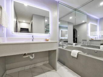 Vanity unit, hanging rail with towels, backlit mirror, spa tun with mirror surround, tiled flooring