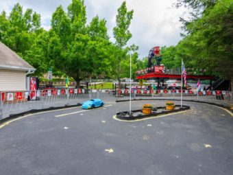 Car track with small pedal cars next to go kart track and wooden building with vending machine