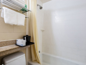 Shelves and rail with towels, toilet, shower tub with shower curtain
