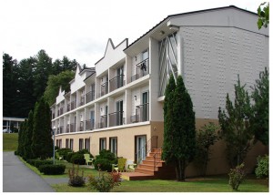 Hotel building showing balconies and landscaping with small trees, small bushes and grassy area