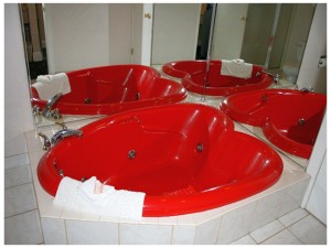Heart shaped whirlpool tub, mirrored walls, bath mat and tiled surround