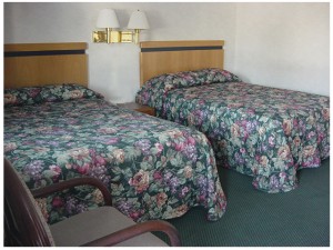 Upholstered chair, two double beds, night stand, wall mounted bedside lights and carpet flooring