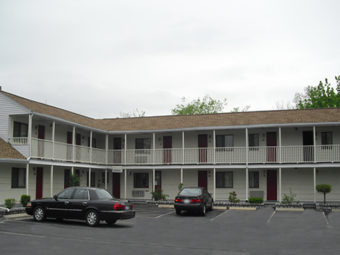 Two storey building showing outside room entrances and parking area with small plants in planters