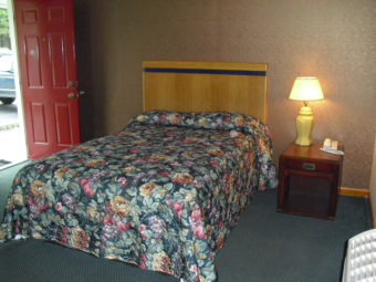Double bed, night stand with telephone and bedside lamp and carpet flooring