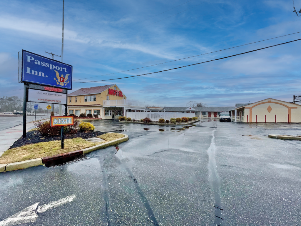 Brand signage, canopied drive through hotel entrance, one story building with exterior room entrances and parking spaces