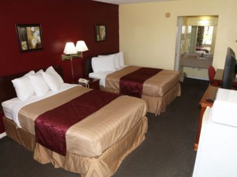Two double beds, art images, wall bedside lights, night stand with telephone, alcove with vanity sink, wall mounted hair dryer, large wall mounted mirror with overhead strip light, desk with upholstered chair, large wall mounted mirror, wall mounted light, wooden unit with tv, fridge, microwave and carpet floor