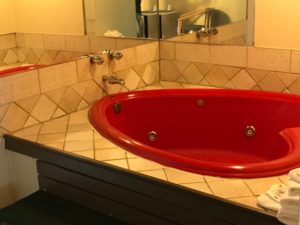 Whirlpool bath, mirrored walls, bath mat, towels, bathroom amenties and tiled surround