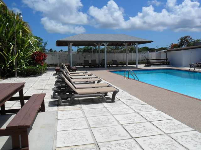 Pool loungers, tropical plants, canopy, outdoor pool with tiled concrete surround