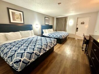 2 king beds, art images, night stand, wall light, desk with lamp and chair, wooden drawer unit, laminate flooring