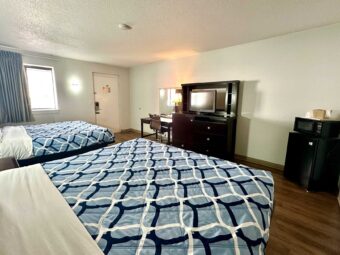 2 king beds, night stand, desk with lamp, telephone and chair, mirror, wooden drawer unit with TV, fridge with microwave, laminate flooring