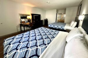 2 king beds, night stand, wall light, art image, desk with lamp, telephone and chair, mirror, wooden drawer unit with TV, fridge with microwave, alcove with vanity unit, hairdryer and mirror, laminate flooring
