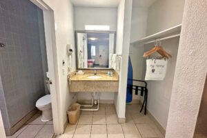 Bathroom with toilet. alcove with vanity unit, mirror, towel rail with towels, hairdryer, ironing board, portable folding luggage rack, hanging rail with hangers