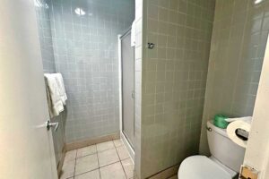 Shower with sliding doors, towels, toilet, tiled flooring