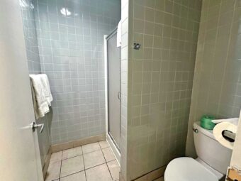 Shower with sliding doors, towels, toilet, tiled flooring