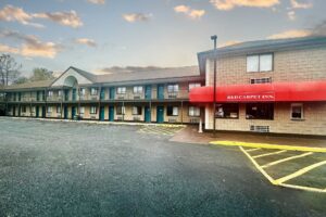Hotel entrance, Two story building with covered walkways and guest room entrances, parking spaces