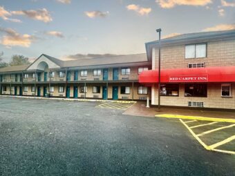 Hotel entrance, Two story building with covered walkways and guest room entrances, parking spaces