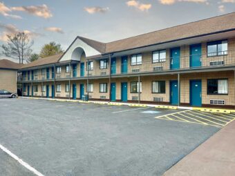 Two story building with covered walkways and guest room entrances, parking spaces