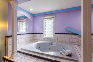 Jacuzzi, tiled surround, large decorive wall mounted mirror and greek style pillars