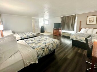 Three double beds, desk with chair, drawer unit with TV, art image, laminate flooring