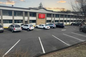 Two story building with exterior guest room entrances and covered walkways, parking spaces