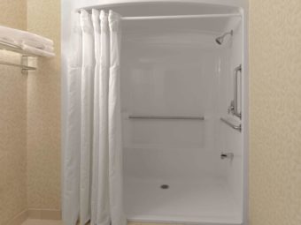 Accessible shower with shower curtain, grab rails, wall mounted towel rail with towels