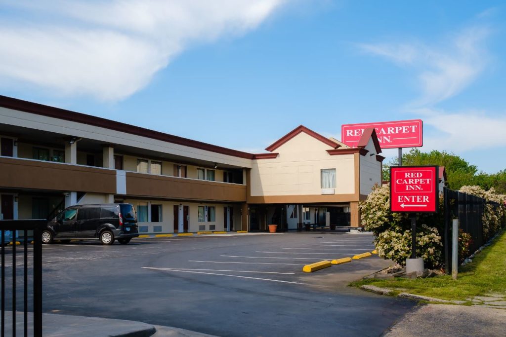 Hotel entrance with canopy, two story building, parking spaces, hotel brand signage