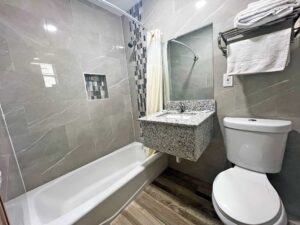 Shower tub with shower curtain, vanity unit with mirror, toilet, shelf with hanging rail and towels