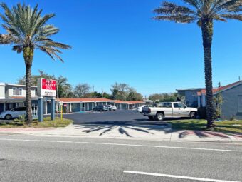 Hotel entrance, brand signage, grassy area, one story building with covered walkways