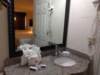 Vanity unit with sinkm towels, bathroom amenities, wall mounted hair dryer and large wall mounted mirror