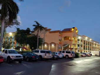 Three storey building, parking area and palm trees