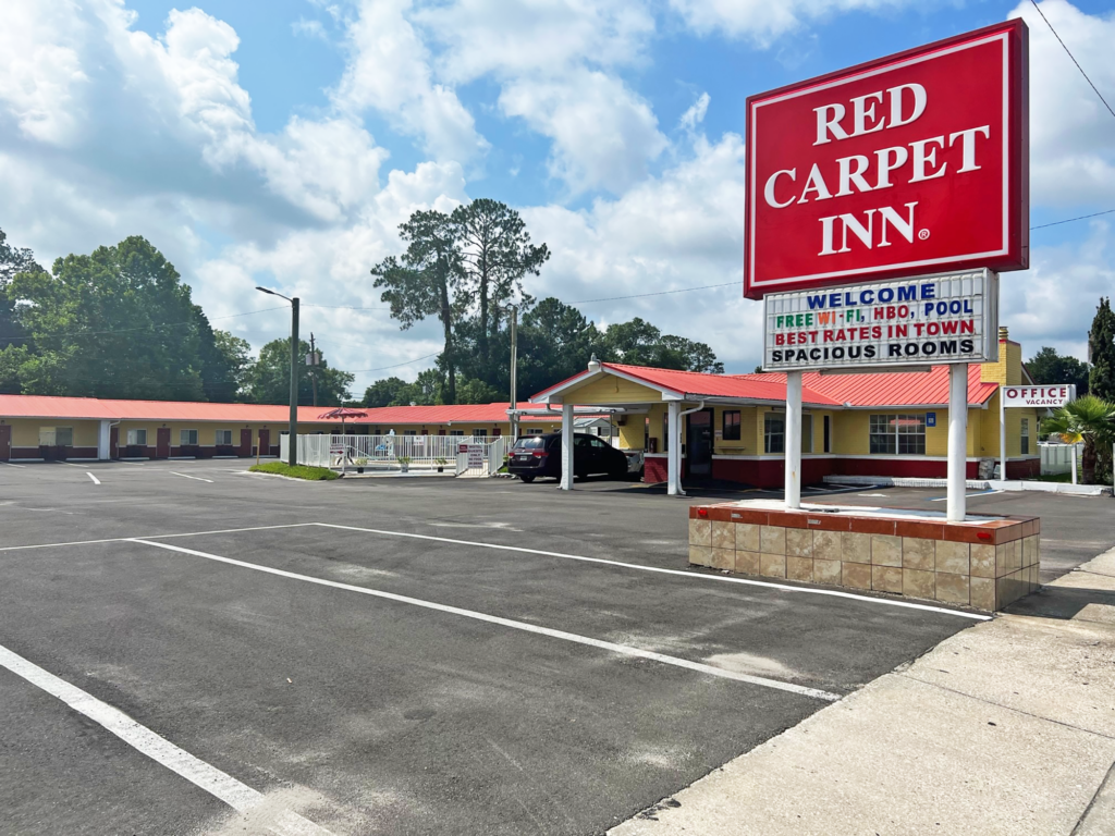 Brand signage, hotel entrance with canopy, parking spaces, exterior guest room entrances