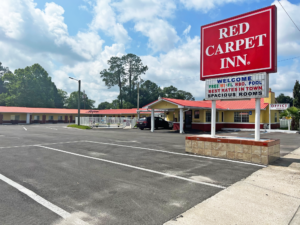 Brand signage, hotel entrance with canopy, parking spaces, exterior guest room entrances