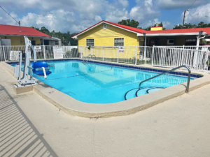 Outdoor pool with concrete surround and pool lift, surrounded by fencing