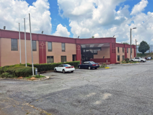 Hotel entrance, landscaping with shrubs, parking spaces