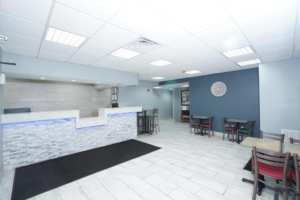 Guest check-in desk, tables and chairs, large clock, tiled flooring