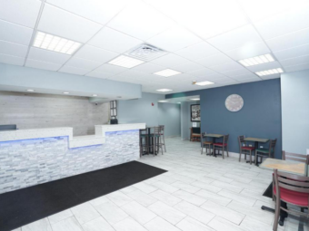 Guest check-in desk, tables and chairs, large clock, tiled flooring