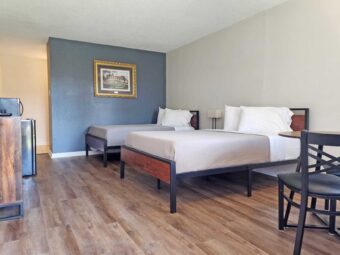Two double beds, night stand with bedside lamp, table and chairs, art image, wooden drawer unit, wall mounted TV, fridge with microwave, laminate flooring