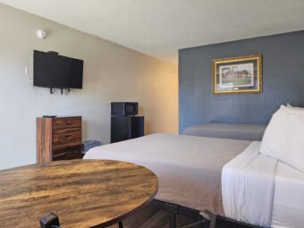 Two double beds, table and chair, art image, wooden drawer unit, wall mounted TV, fridge with microwave