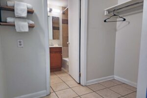 Shelves with towels, shelf with hanging rail and hanger, doorway to bathroom, tiled flooring