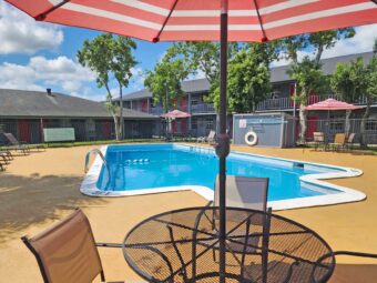 outdoor pool, patio tables with umbrella and chairs, sun loungers
