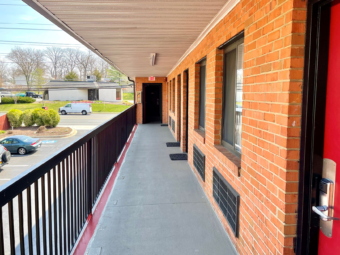 Exterior entrances to rooms, covered walkway, parking spaces, small shrubs