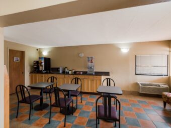 breakfast display counter with cereal dispenser, drink dispenser, microwave, tables and chairs, guest information leaflet stand, tiled flooring