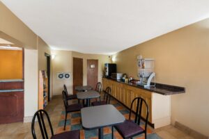 breakfast display counter with cereal dispenser, drink dispenser, microwave, tables and chairs, guest information leaflet stand, tiled flooring