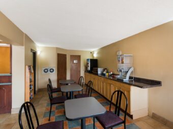 breakfast display counter with cereal dispenser, drink dispenser, microwave, tables and chairs, guest information leaflet stand, tiled flooring