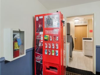 Wall mounted fire extinguisher, soda cans vending machine outside guest laundry area with washing machine, dryer and self dispensing ice machine