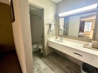 Vanity unit with ice bucket, mirror, hairdryer, towel rail with towels, doorway leading to bathroom