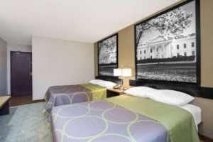 Two queen beds, night stand with bedside lamp, telephone and clock, carpet flooring